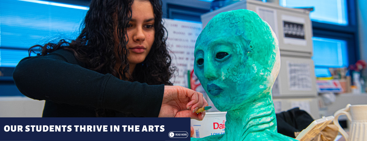Teenage girl sculpting a green alien